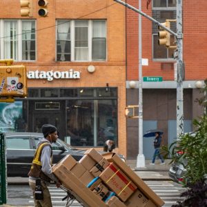 man in green jacket and black pants standing in front of brown building during daytime